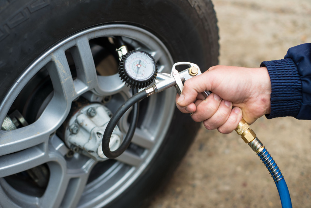 mechanic holding a pressure hose to add air to a car tire