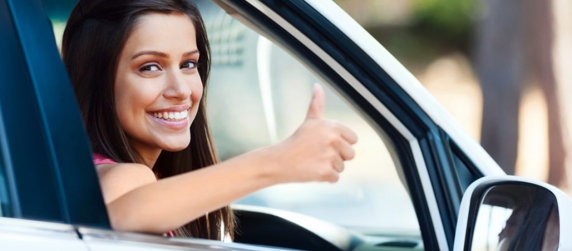 a happy woman in a car making a thumbs up